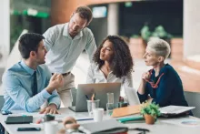 Group of 4 people engaged in a meeting discussion in an office.