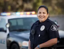 Female police officer standing by a police car