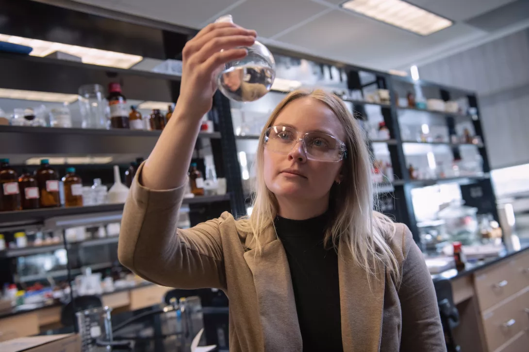 Student examining chemical flask in chemistry lab