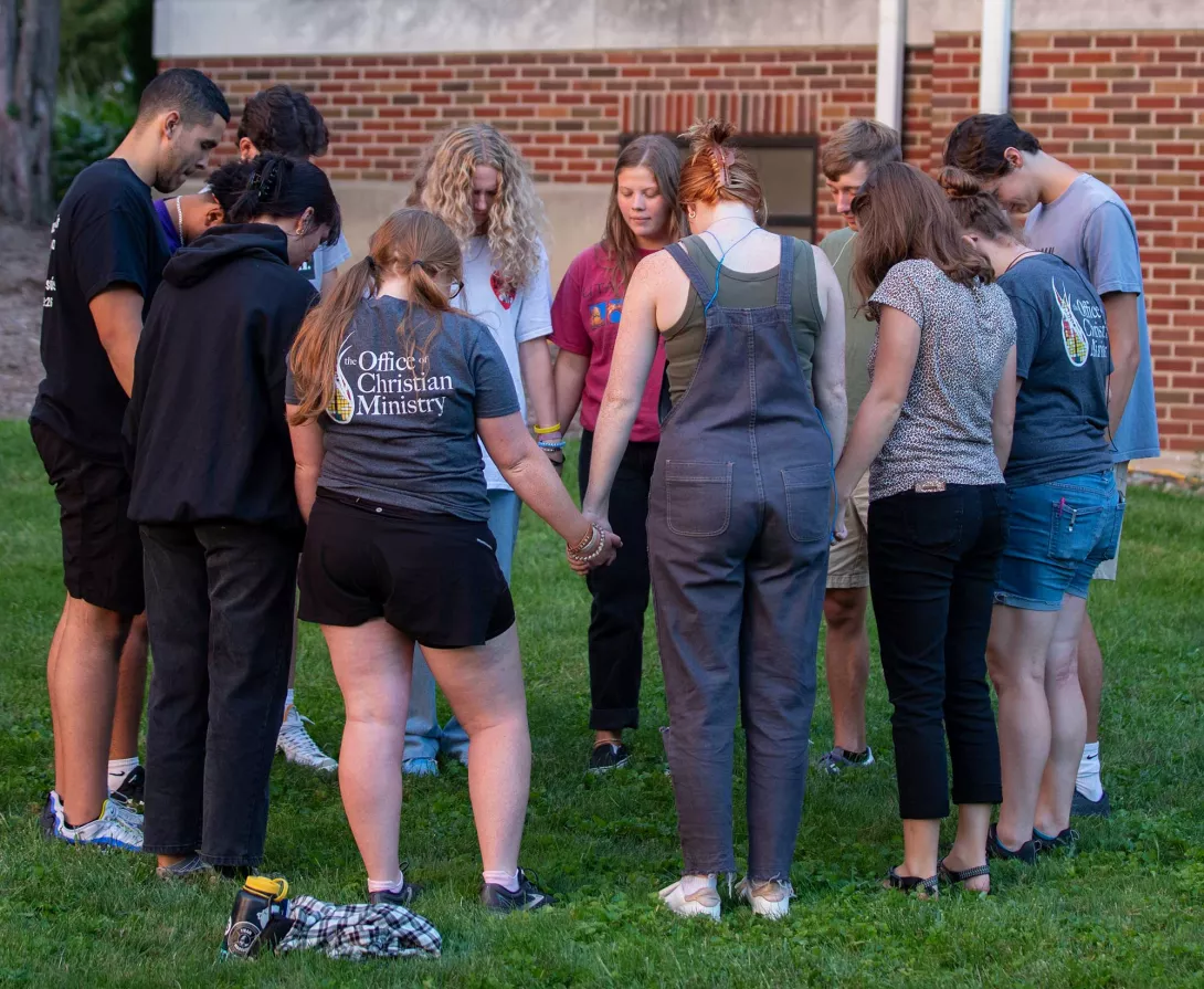 Group of students standing in a circle praying